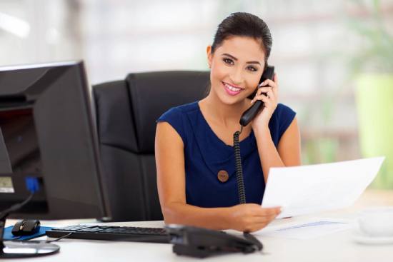 A woman sitting at her desk talking on the phone.