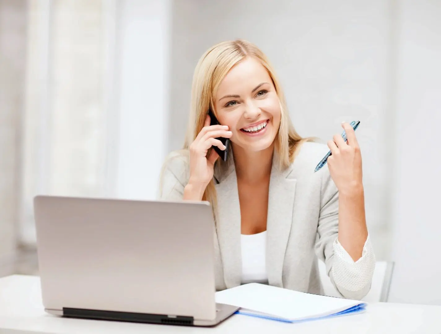 A woman sitting at her desk talking on the phone.