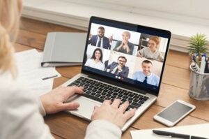 A person is on his laptop with several people in the screen.