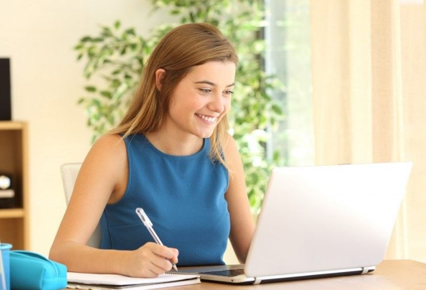 A woman sitting at a table with a laptop.