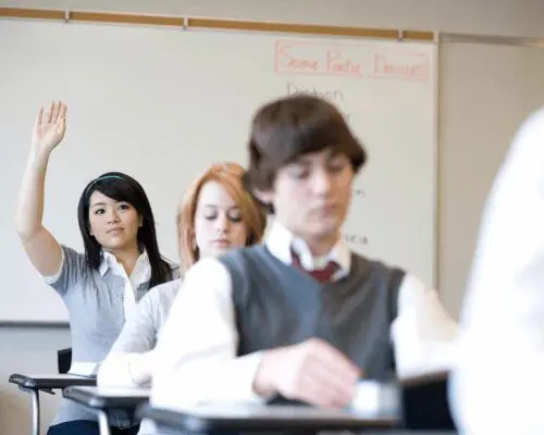 A group of students sitting at desks in front of a whiteboard.